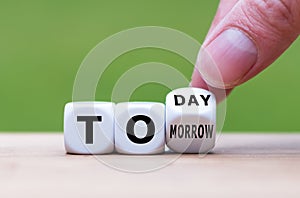Hand turns a dice and changes the word `tomorrow` to `today`, or vice versa photo