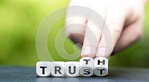 Hand turns dice and changes the word Trust to Truth.