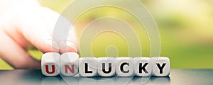 Hand turns dice and changes the word `unlucky` to `lucky`.