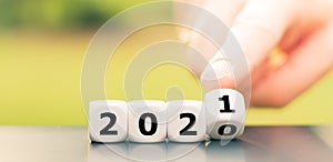 Hand turns dice and changes the year `2020` to `2021`.