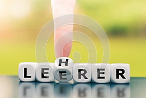 Hand turns a dice and corrects a typo by changing the German word `Leerer` `empty` in English to `Lehrer` `teacher` in