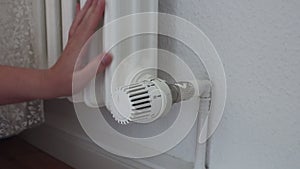 Hand turns the heating system thermostat and checks the temperature