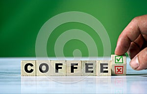 hand turns the wooden cube and changes the word COFFEE with green positive tick check box and red reject X check box. Yes or no