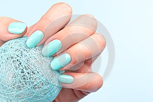 Hand with turquoise nails with ball