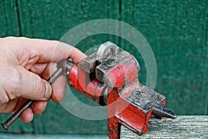 Hand twists the handle of the desired red vise