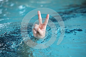 Hand with two fingers up in the victory or peace symbol,above water