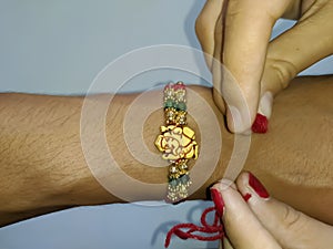 A hand tying rakhi on a hand wrist on the event of rakshabandhan