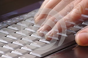 Hand typing fast on laptop keyboard
