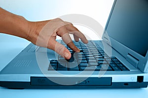 Hand typing on a laptop