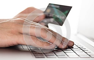 Hand typing on laptop with credit card