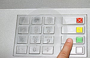 Hand typing the secret code in the keyboard of an ATM