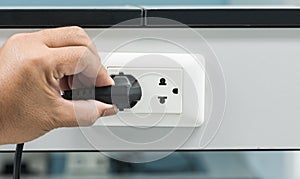 Hand unplugging a plug from a socket photo