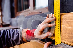 Hand of unrecognizable worker, doing facade, measuring wooden bo