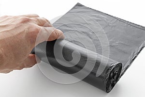 hand unwinds a roll of plastic garbage bags,