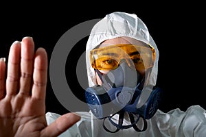 Hand up stop sigh woman in a chemical protective clothing and antigas mask with glasses at white background, Women scientist in