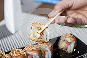 Hand using chopsticks with sushi