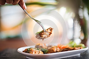 Hand using fork to eating fried chicken in the restaurant