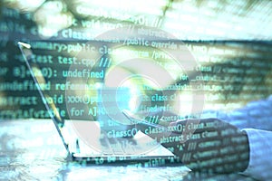 Hand using laptop and abstract coding text interface on screen