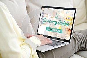 Hand using laptop computer with grocery online shopping over blu