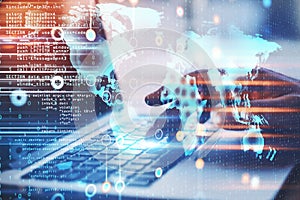 Hand using laptop with world map hologram on creative glowing programming backdrop