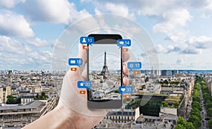 Hand using mobile smart phone taking photo of Eiffel tower in Paris, France with social media and social network notification icon