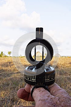 Hand using old fashioned prismatic compass