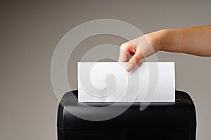 Hand using paper shredding machine against gray background