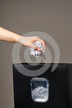 Hand using paper shredding machine against gray background