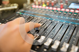 hand using professional audio mixing console to control the sound