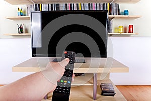 Hand using remote control in front of the TV