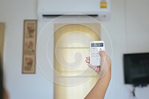 Hand using a remote control to activating air conditioning