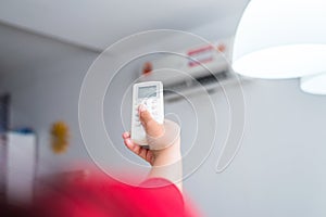 Hand using a remote control to activating air conditioning