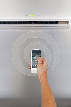Hand using a remote control to activating air conditioning.
