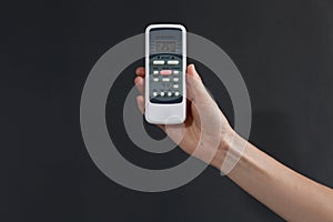 Hand using a remote control to activating air conditioning on the dark background.