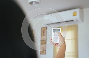Hand using a remote control to activating air conditioning