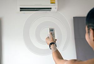 Hand using a remote control to activating air conditioning in room