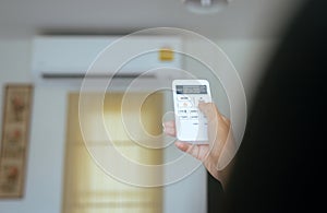 Hand using a remote control to activating temperature air conditioning