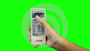 Hand using a remote control to change the temperature of air conditioner. Green screen