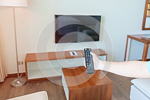 Hand using remote controller for adjust Smart TV inside the modern room at home. Apartment living concept