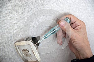 Hand Using Screwdriver to Disassemble Damaged Wall Outlet at Home During Daytime