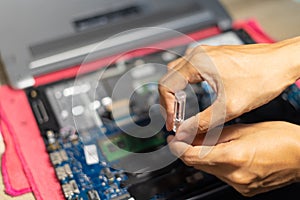 the hand is using a screwdriver to tighten the nut. To change the battery of a notebook computer by yourself. Changing electronic