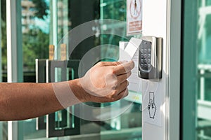 Hand using security key card scanning to open the door to entering private building. Home and building security system photo