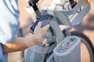 hand using smartphone for renting bicycle