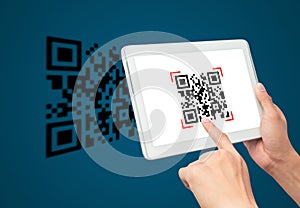 Hand using tablet computer scan Qr code on blue background.