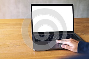 A hand using and touching on laptop touchpad with blank white desktop screen on wooden table
