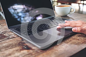 hand using and touching on laptop touchpad on wooden table