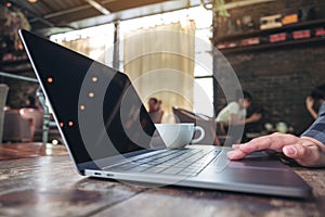 Hand using and touching on laptop touchpad on wooden table