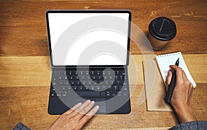 A hand using and touching tablet keyboard with blank white desktop screen as computer pc while writing