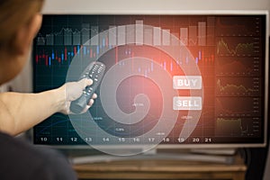 Hand Using the TV remote to connect electrical appliances concept, featuring stock tickers or graphs, cryptocurrency