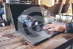 Hand using and typing on laptop touchpad on wooden table